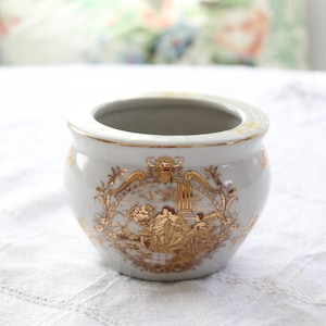 May include: A white ceramic mug with a black handle and the text "But First, Coffee" in a bold, black font. The mug is set against a blurred background, highlighting its clean design.