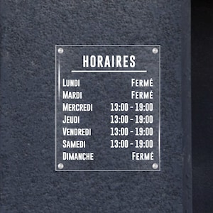 Könnte beinhalten: Ein weißes Schild mit schwarzem Text, auf dem die Öffnungszeiten eines Geschäfts aufgeführt sind. Das Schild trägt oben die Aufschrift "HORAIRES" und listet die Wochentage mit den entsprechenden Öffnungszeiten auf. Das Schild zeigt "FERMÉ" für geschlossen an Montag, Dienstag und Sonntag.
