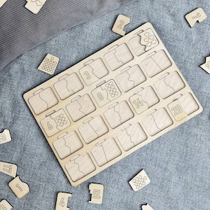 May include: Wooden puzzle board with suitcase-shaped slots and numbered pieces. The board has 24 slots, with numbers and heart-shaped designs on the pieces. The puzzle is made of light-colored wood and is scattered on a gray surface.