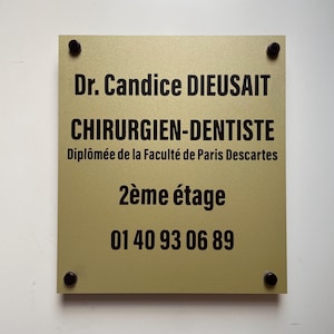 Peut inclure: Une plaque dorée avec du texte noir qui indique "Dr. Candice DIEUSAIT CHIRURGIEN-DENTISTE Diplômée de la Faculté de Paris Descartes 2ème étage 01 40 93 06 89"