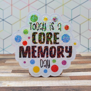 May include: A white sticker with a glittery finish and colorful dots. The sticker says "Today is a CORE MEMORY day".