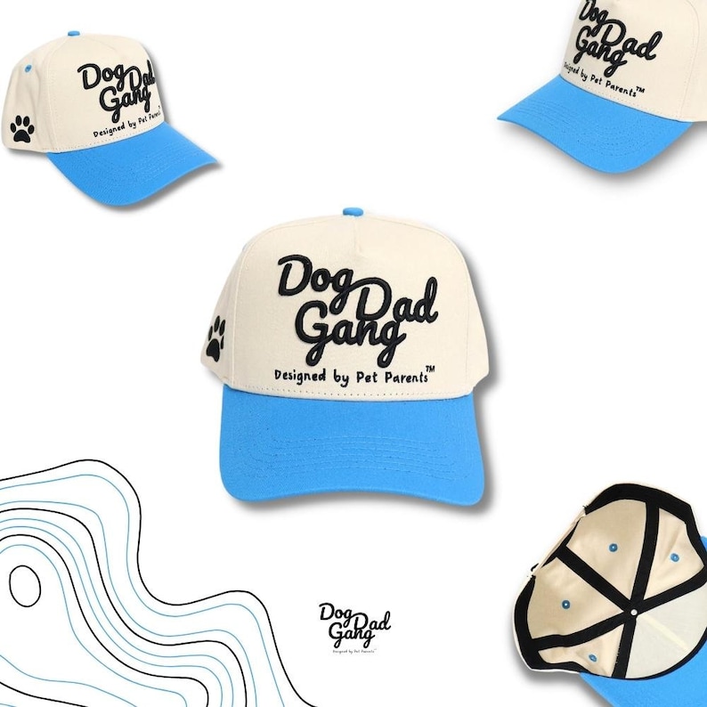 May include: Cream-colored baseball cap with a light blue brim. The cap features the text "Dog Dad Gang" in black script, with "Designed by Pet Parents" below. A paw print is on the side.