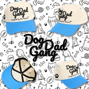 May include: A collection of baseball caps with the text "Dog Dad Gang" in black script. The caps have a cream-colored crown and a light blue brim. The background features a repeating pattern of dog and cat-themed doodles.