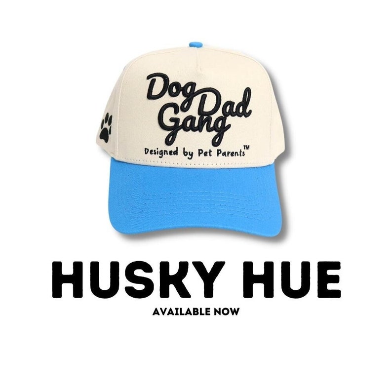 May include: A cream-colored baseball cap with a light blue brim. The cap features the text "Dog Dad Gang" in black script, with a paw print on the side. The text "Designed by Pet Parents" is below the main text.