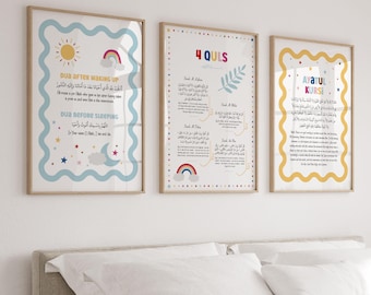 May include: Three framed art prints with Islamic text. The prints feature colorful designs with text in Arabic and English. The frames are a light wood color. The prints are displayed above a bed with white bedding.