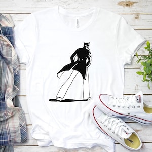 Könnte beinhalten: Weißes T-Shirt mit einer schwarzen Silhouette einer Person in einem Mantel und Hut. Die Person geht mit dem Rücken zum Betrachter.