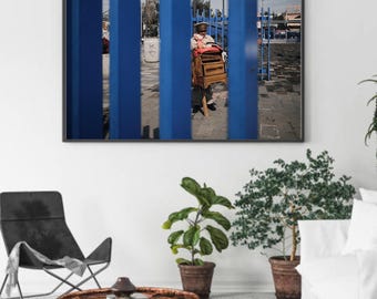 Póster enrollado de vendedor ambulante tras rejas azules / Fotografía urbana