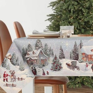 Peut inclure: Nappe de Noël festive représentant un village d'hiver enneigé avec des maisons, des arbres et des personnages. Le motif comprend le Père Noël avec un renne, une calèche et un bonhomme de neige. La nappe est posée sur une table en bois.