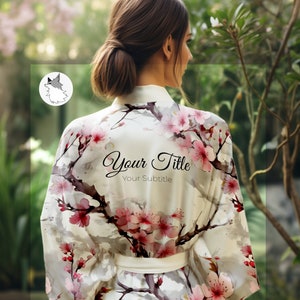 Puede incluir: Una bata blanca con estampado floral rosa y blanco. La bata tiene un cinturón de atar y está hecha de una tela suave y sedosa. El texto "Your Title" y "Your Subtitle" está impreso en la bata.