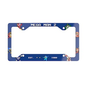 May include: A blue license plate frame featuring the text "MEGA MAN 2" at the top and "EST. 1988" at the bottom. The frame is decorated with pixelated characters from the Mega Man video game series.