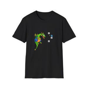 May include: Black t-shirt with a cartoon dragon in green, orange, and blue. A small blue figure is shooting at the dragon. The design also includes three white squares. The dragon is facing right.