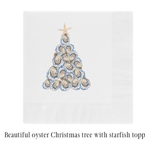 May include: A white paper napkin with a blue and white oyster Christmas tree with a starfish topper. The napkin is folded in half and the tree is in the center of the napkin.
