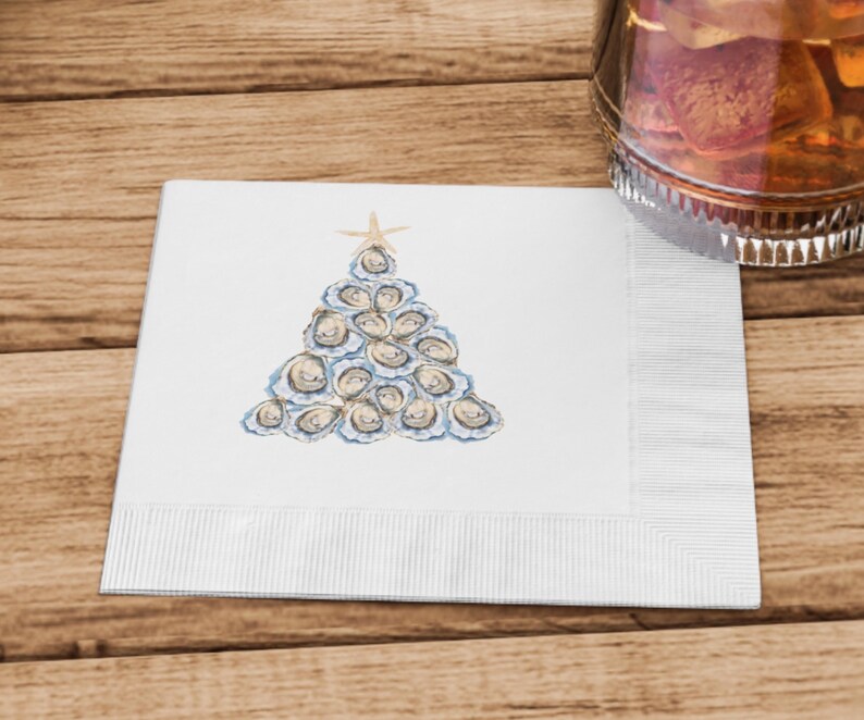 May include: White paper napkin with a watercolor illustration of a Christmas tree made of oyster shells. The tree is topped with a gold star.