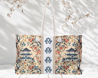 May include: A large tote bag with a cream-colored background featuring a repeating pattern of a pagoda, birds, and flowering branches in shades of blue, coral, and brown. The bag has white rope handles and a central panel with monogrammed initials.