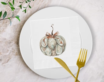 May include: A white paper napkin with a watercolor illustration of a pumpkin, adorned with a brown bow and stem. The napkin is placed on a white plate, with a gold fork and knife. The image has a fall theme.