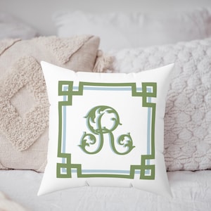 Peut inclure: Coussin carr&eacute; blanc avec une bordure verte et bleue et un &laquo; R &raquo; d&eacute;coratif vert au centre. Le coussin est pos&eacute; sur une surface blanche avec d'autres coussins d&eacute;coratifs en arri&egrave;re-plan.