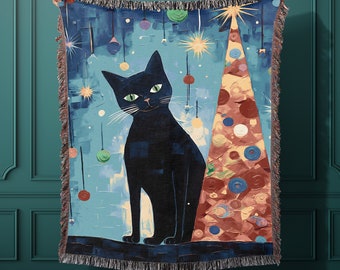 May include: A woven throw blanket featuring a black cat standing next to a colorful Christmas tree with ornaments. The background is a blue and green abstract design.
