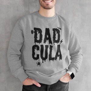 May include: A gray sweatshirt with a black graphic that says "Dadcula" with dripping letters and a spider.