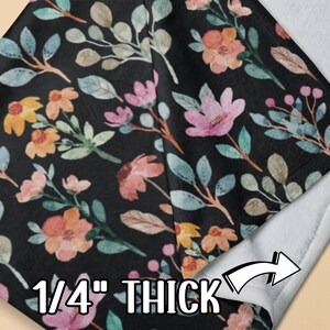 May include: A black blanket with a floral pattern featuring pink, yellow, and blue flowers and leaves. The blanket is 1/4 inch thick and has a white backing.