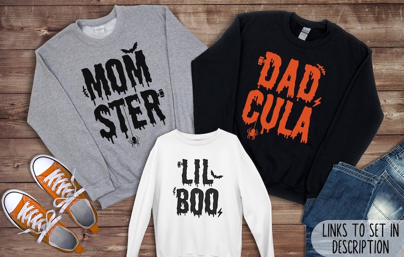 May include: Three Halloween themed sweatshirts with dripping text. The grey sweatshirt says "Momster" with a spider and bat. The black sweatshirt says "Dadcula" with a spider. The white sweatshirt says "Lil Boo" with a bat and lightning bolt.