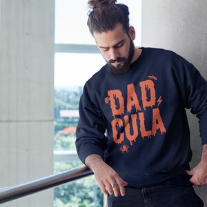 May include: A navy blue sweatshirt with a dripping orange graphic that says "Dadcula" with a spider underneath.