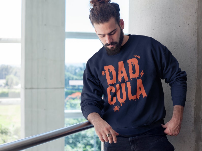 May include: A navy blue sweatshirt with a dripping orange graphic that says "Dadcula" with a spider underneath.