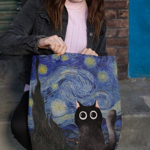 May include: A black tote bag with a print of Vincent van Gogh's Starry Night featuring a black cat with large eyes.