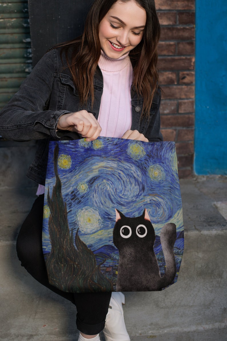 May include: A black tote bag with a print of Vincent van Gogh's Starry Night featuring a black cat with large eyes.