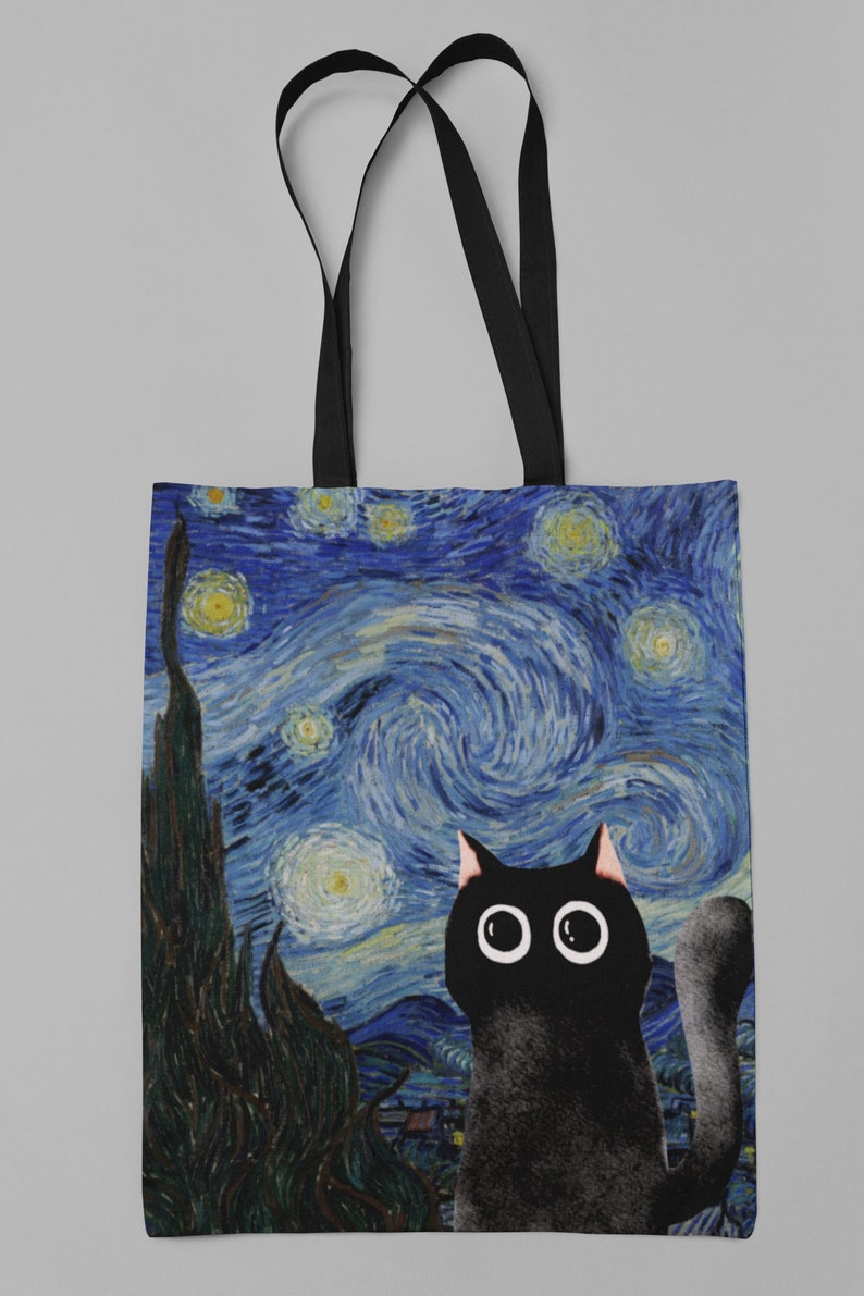 May include: A black canvas tote bag with black straps. The bag features a print of Vincent van Gogh's "Starry Night" with a black cat looking up at the stars.