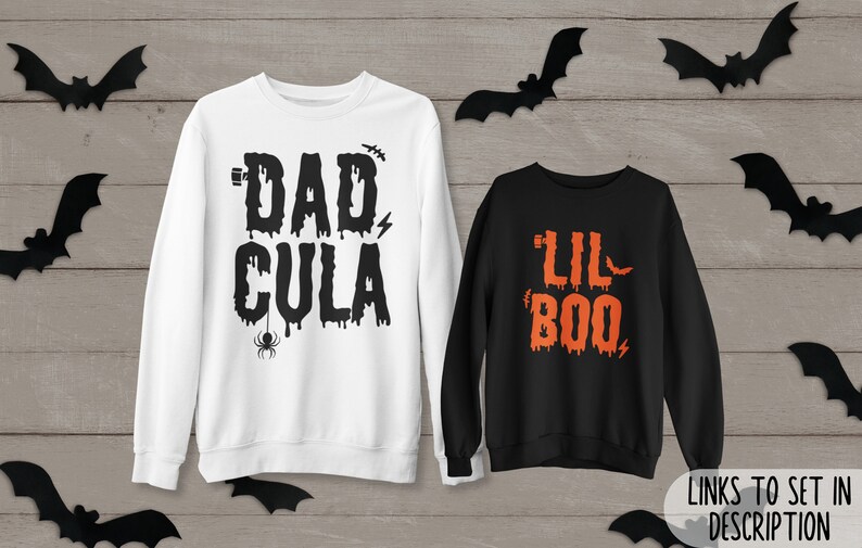 May include: Two Halloween themed sweatshirts. One white sweatshirt with the text "DAD CULA" in black dripping letters. The other black sweatshirt with the text "LIL BOO" in orange dripping letters.