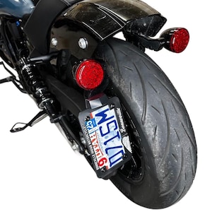 May include: A black motorcycle with a red taillight and a number plate that reads "911MAY 123" with the text "Bonneville Indian Motorcycle" underneath. The motorcycle has a black fender and a black tyre.