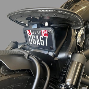 May include: Black motorcycle with a black leather seat and a black license plate holder. The license plate reads "3 UTAH 24 06A67".