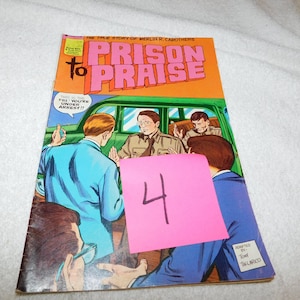 May include: Vintage comic book titled "Prison to Praise" with a colorful illustration. The cover features a scene with several men, a green car, and the text "This is the FBI, you're under arrest!!" A pink sticky note with the number 4 is attached.