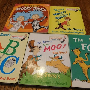 May include: A collection of five Dr. Seuss board books including Dr. Seuss's Spooky Things, There's a Wocket in My Pocket, Dr. Seuss's ABC, Mr. Brown Can Moo! Can You?, and The Foot Book, featuring colorful illustrations and iconic character designs.