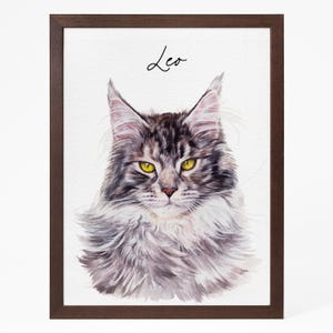 May include: Watercolor portrait of a Maine Coon cat named Leo, set in a dark brown wooden frame. The cat has gray and brown fur with yellow eyes. The name "Leo" is written in cursive above the cat's head.