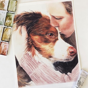 May include: Watercolor painting of a brown and white dog being embraced by a person. The dog has brown fur and a white muzzle. The person is kissing the dog on the head. Watercolor paints and a tube of white paint are in the background.
