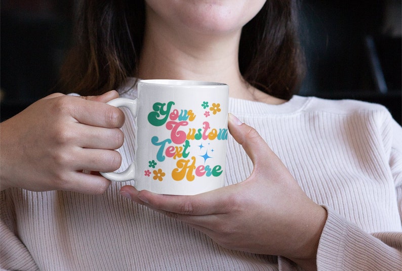 May include: White ceramic mug with a colorful retro design. The text on the mug reads "Your Custom Text Here" with flowers and stars.