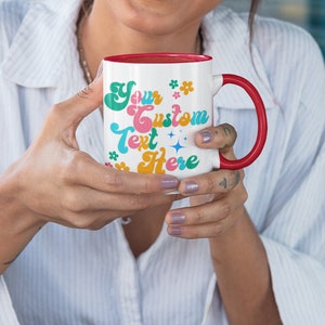 May include: White ceramic mug with a red rim and handle. The mug has a colorful design with the text "Your Custom Text Here" in a retro font.