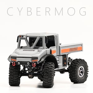 May include: A gray and orange toy truck with a roll cage and a flatbed. The truck has black tires and a black chassis. The truck is on a white background.