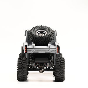 Puede incluir: Un camión de juguete gris con una rueda de repuesto montada en la parte trasera. El camión tiene seis ruedas y está hecho de plástico.