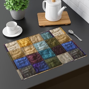 May include: A rectangular placemat with a patchwork design. The placemat features squares of various colors, including yellow, blue, purple, and green. The placemat is made of a textured fabric and is placed on a dark surface.