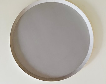 May include: A round, white cardboard cake plate with a slightly raised edge.