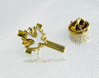 May include: Gold-tone pin with a white dove on a cross design. The pin is on a white background.