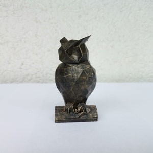 May include: A black and gold geometric owl figurine with a detailed, textured finish. The owl is perched on a small base.