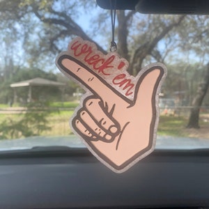 May include: A car air freshener with a hand pointing and the words "wreck 'em" written in red.