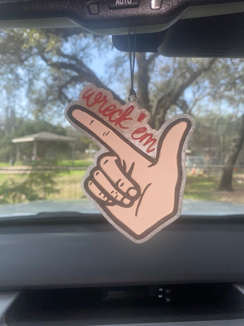 May include: A car air freshener with a hand pointing and the words "wreck 'em" written in red.