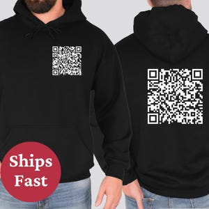 May include: Black hoodie with a white QR code printed on the front and back. The hoodie has a drawstring hood and a kangaroo pocket.