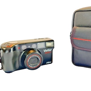 May include: Black Vivitar 400i Zoom camera with a matching black case. The camera has a red accent around the lens and the case has a red stripe. The camera strap is brown and black.