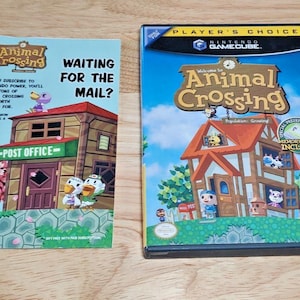 May include: A Nintendo GameCube game case and a promotional booklet for "Animal Crossing." The game case features a colorful illustration of a house with characters. The booklet says "Waiting for the Mail?" and has a post office illustration.