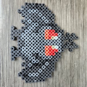 Könnte beinhalten: Ein Pixel-Art-Design in Schwarz, Weiß und Rot von einer Kreatur mit einem großen Kopf und einem kleinen Körper. Die Kreatur hat ein rotes und weißes Design auf dem Kopf.